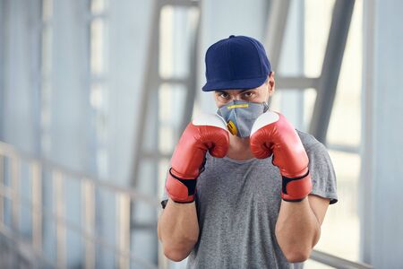 A guy in a protective mask and boxing gloves fights against viruses. Coronavirus covid-19 concept photoの写真素材