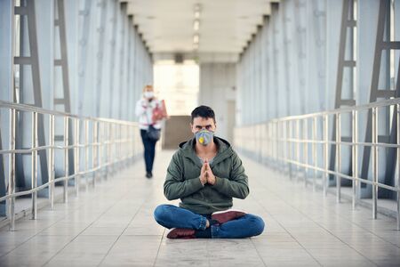 A man is meditating at empty public place in a mask. Coronavirus concept photo.の写真素材