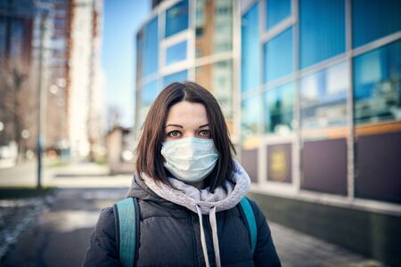 Woman in mask on street because epidemic of coronavirus in city. Protection against virus and infectionの写真素材
