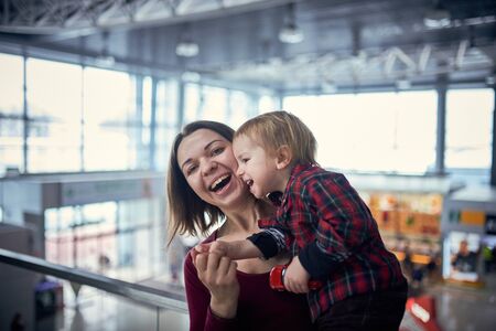 Cute two year old boy on mother's hands during walk in public place.の写真素材