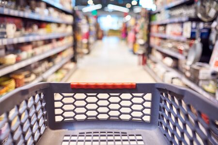 Abstract blurred photo of empty trolley in supermarket bokeh background. Empty shopping cart in...