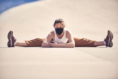 Woman is doing yoga at empty city in a mask. Epidemic of Coronavirus concept photo.