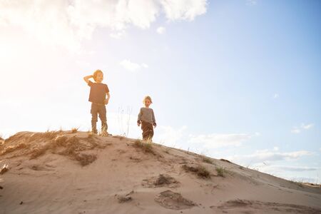 Happy boys standing on sand at sunny day.の写真素材
