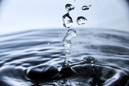 Boiling water splash with steam on blue background closeup.