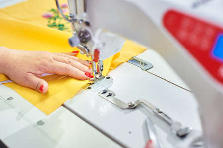 Industrial sewing machine and hand seamstress. Close-up.
