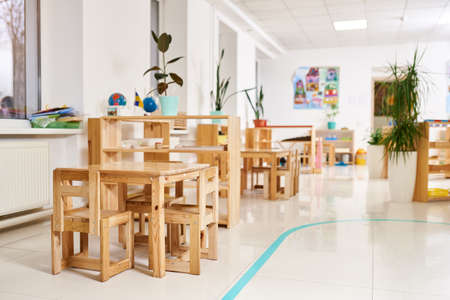 Light class in Montessori kindergarten. wooden children's table with chairs in the foreground. nobody.の写真素材