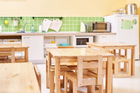 Light modern kitchen in Montessori kindergarten. wooden children's table with chairs in the...