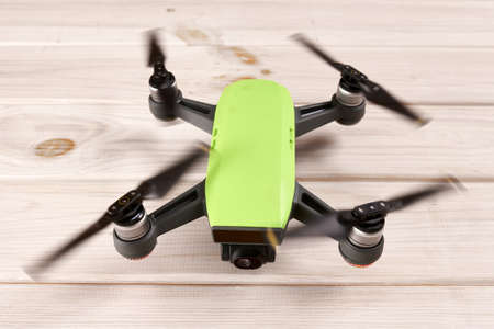 Drone with running engines and rotating propellers standing on the table and ready to fly.
