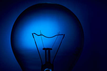 Electric bulb lamp with a spiral on a blue background.の写真素材