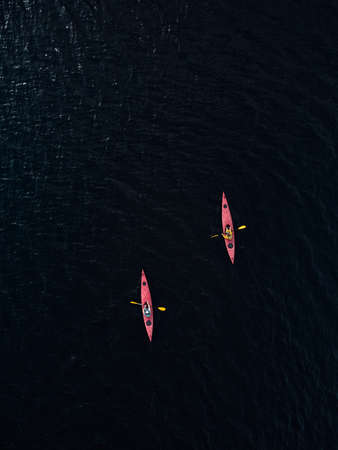 aerial view of two red kayaks in dark blue lake water. Drone photo