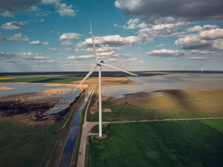 Aerial top view of wind turbines and agriculture field near the sea at sunsetの写真素材
