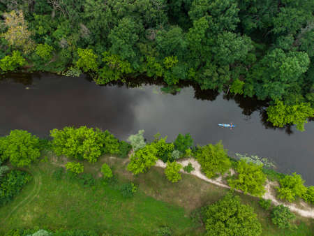 aerial view of a large group of kayaks traveling on a forest river on a summer day