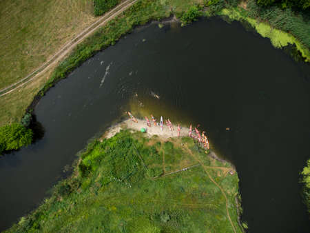 aerial view of a large group of kayaks traveling on a forest river on a summer day