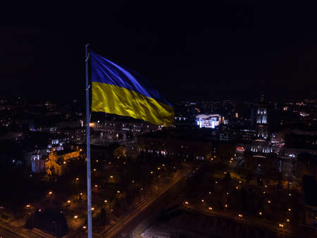 Ukrainian flag in the wind. Blue Yellow flag Against the city at nightの写真素材