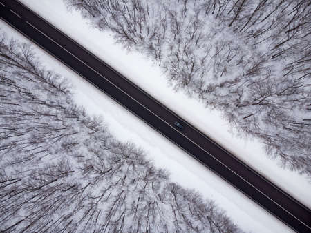 Aerial view of winter road and forest with snow covered trees.の写真素材