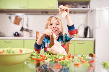 An adorable 4 year old preschool boy cooking fresh vegetable salad in the kitchen at home.の写真素材