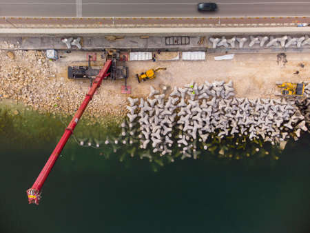 Aerial top view of breakwater construction. Bulldozer and crane on a pile of boulders in the seaの写真素材