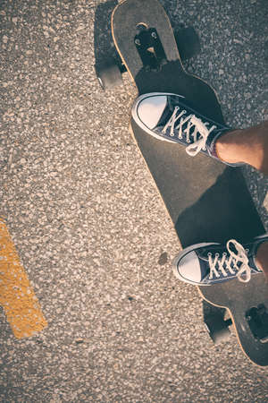 Feet of man in sneakers on a longboard at the eveningの写真素材