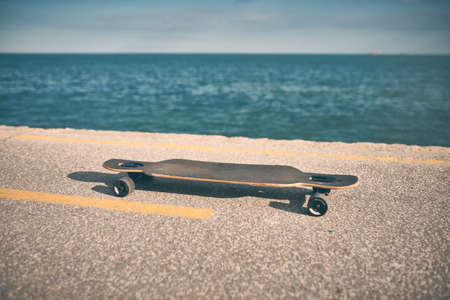 longboard on asphalt against the background of the sea without people
