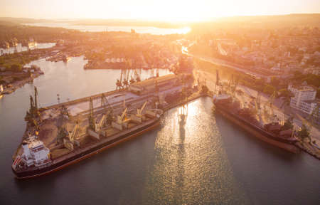 Aerial view of big cargo ship bulk carrier is loaded with grain of wheat in port at sunsetの写真素材