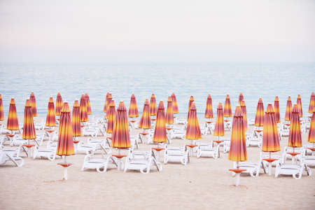View of umbrellas and chairs on sandy beach and sea. Empty beach waiting for tourists.の写真素材