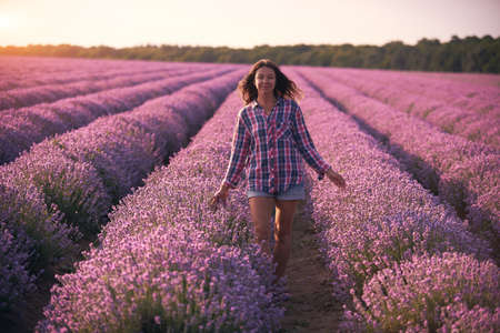Young woman in multicolor plaid shirt in beautiful Lavender field.