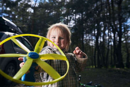A little joyful boy playing with toy propeller in the forestの写真素材