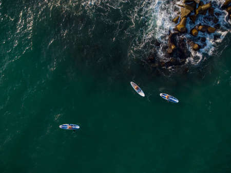 Aerial view of 3 men exercising sup board or Stand Up Paddle board in the sea