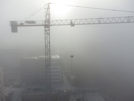 tower cranes on a construcion site with dense fog aerial viewの写真素材