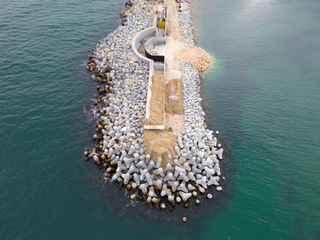 Heavy construction equipment is building a breakwater. Pouring concrete on a pier under construction in the sea. aerial view.の写真素材