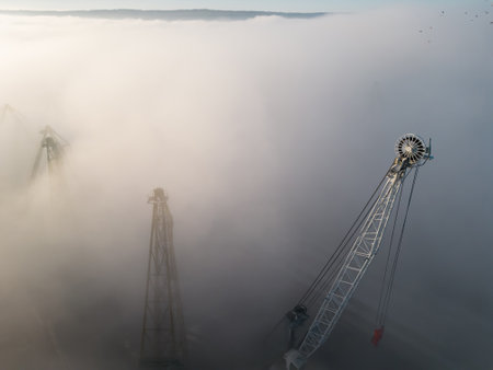 Drone flight over the cranes in port industrial zone in morning fogの写真素材