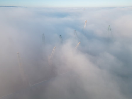 Drone flight over the cranes in port industrial zone in morning fogの写真素材