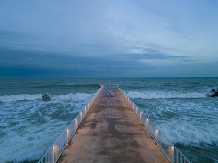 illuminated pier with dramatic sky over stormy dark sea at evening, Varna Bulgariaの写真素材