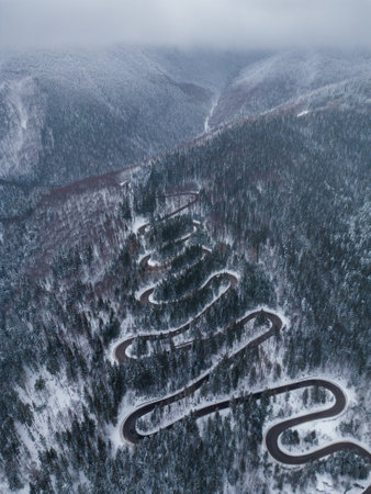 Aerial top down view of winter winding road in the forest, Transylvania, Romania.