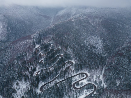 Aerial top down view of winter winding road in the forest, Transylvania, Romania.