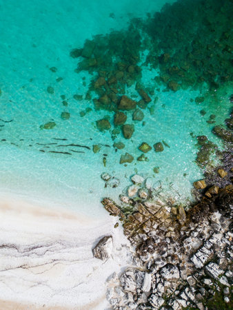 The beach with white marble pebbles and turquoise sea on the Greek island of Thassos is a breathtaking natural wonder. aerial view. The contrast of the pristine white pebbles against the vivid blue sea creates a mesmerizing view.の写真素材