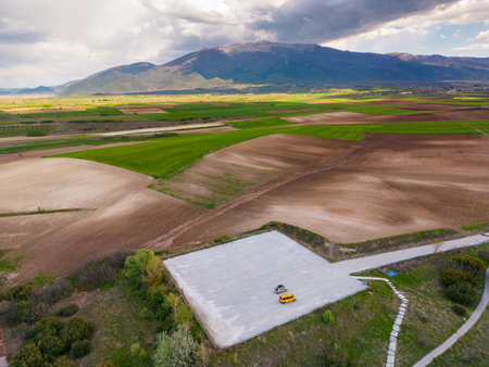 From above, the agricultural fields nestled amidst towering mountains in Greece create a stunning aerial top viewの写真素材