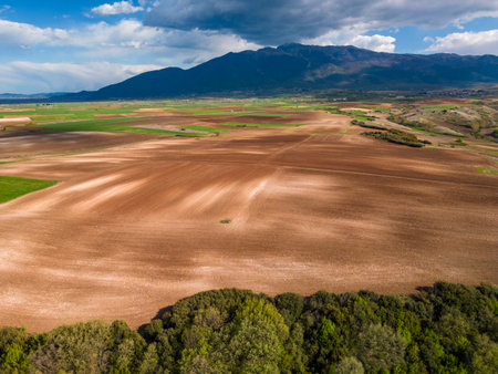 From above, the agricultural fields nestled amidst towering mountains in Greece create a stunning aerial top viewの写真素材