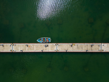 aerial view of a serene dock in the sea, with several fishing boats tied up and bobbing in the calm waters. Its a peaceful scene that captures the essence of coastal living.の写真素材