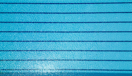 An aerial view reveals an empty pool, devoid of swimmers. The calm water reflects the surroundings,...