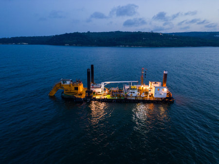 Aerial view of a dredge vessel with a dredging bucket, actively deepening the navigational fairway at sea, ensuring safe navigation.の写真素材