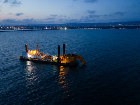 Aerial view of a dredge vessel with a dredging bucket, actively deepening the navigational fairway at sea, ensuring safe navigation.の写真素材