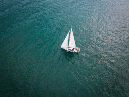 Aerial view of a sailboat gracefully gliding across the boundless waves of the sea.の写真素材
