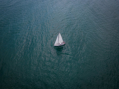 Aerial view of a sailboat gracefully gliding across the boundless waves of the sea.の写真素材
