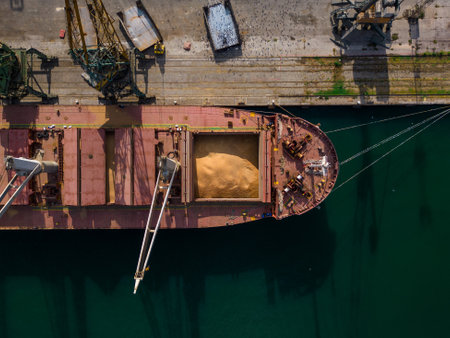 cargo ship or bulk carrier loaded to the brim with grain is preparing for departure, working sailors on deck are completing work, aerial viewの写真素材