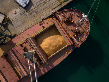 cargo ship or bulk carrier loaded to the brim with grain is preparing for departure, working sailors on deck are completing work, aerial viewの写真素材