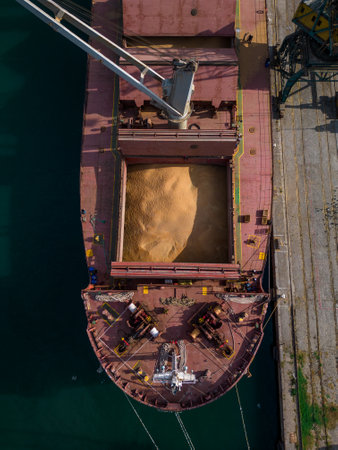cargo ship or bulk carrier loaded to the brim with grain is preparing for departure, working sailors on deck are completing work, aerial viewの写真素材