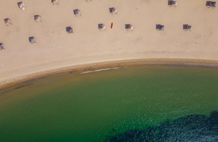 aerial view of a sandy deserted beach with straw umbrellas, a red sea kayak and a calm turquoise seaの写真素材