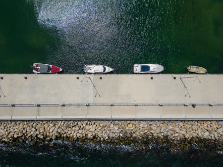 aerial top down view of a serene dock in the sea, with several fishing boats tied up and bobbing in the calm waters. It's a peaceful scene that captures the essence of coastal living.の写真素材