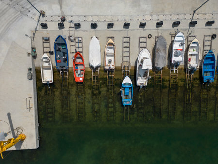 aerial top down view of a serene dock in the sea, with several fishing boats tied up and bobbing in the calm waters. It's a peaceful scene that captures the essence of coastal living.の写真素材